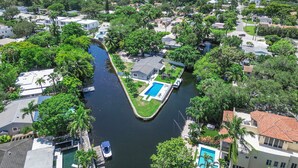 Vista aérea de un área residencial con un canal, casas y una piscina.