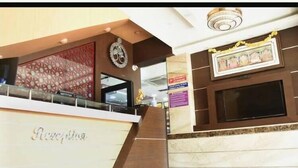 A reception area with a marble counter, a clock, and a framed artwork on the wall. - Le Emerald Residency (Chennai)