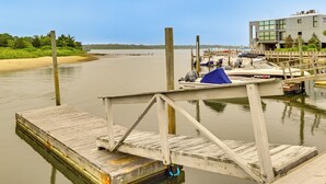 Eine hölzerne Mole führt in ein ruhiges Gewässer, wo ein Boot namens „Palm Beach“ vor Anker liegt.