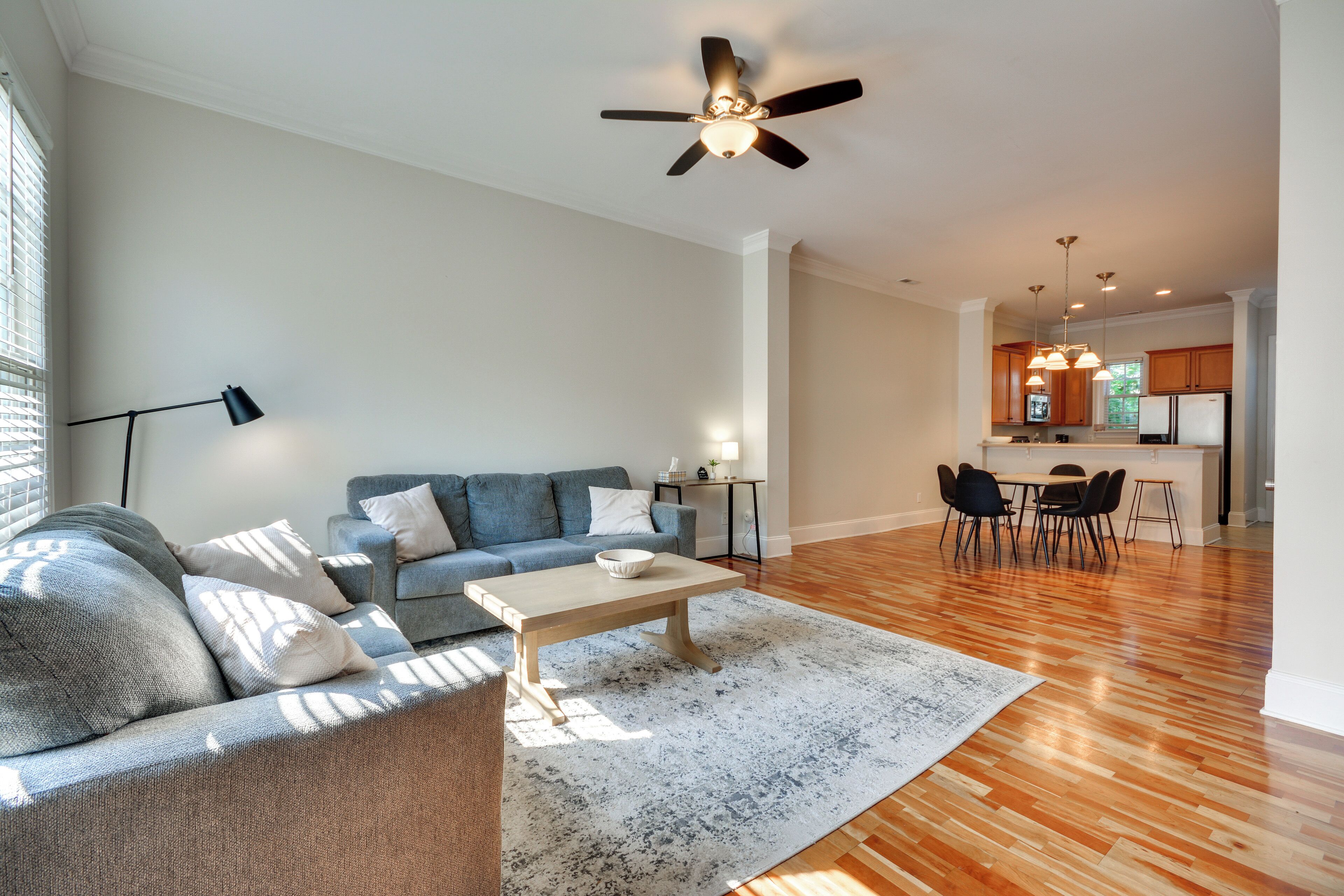 Uma sala moderna com sofá, mesa de centro e um espaço de jantar com cadeiras e mesa.