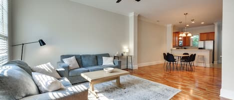 Uma sala moderna com sofá, mesa de centro e um espaço de jantar com cadeiras e mesa.