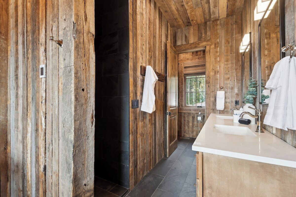 A wooden interior with a bathroom featuring a sink, mirror, and towel rack.