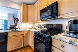 Una cocina moderna con gabinetes de madera, estufa negra, microondas y cafetera.