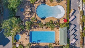 Luchtbeeld van een resort met een groot rechthoekig zwembad, een kleiner rond zwembad en een overdekt zitgedeelte.