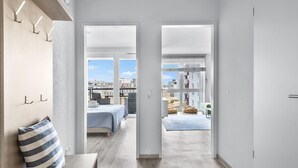 Een modern appartement met een ruim balkon, een bed en een zithoek met uitzicht op de stad.