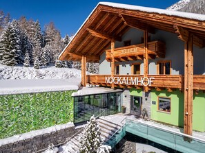 A wooden chalet with a glass balcony, a sign reading '3D FILM', and a view of snow-covered trees.