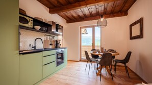 A kitchen with a wooden ceiling, a dining area with a table and chairs, and a view through a glass door. - Idyllic holiday apartments for travel groups (Kremsbrücke)