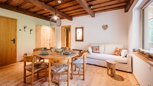 A wooden dining table with chairs, a sofa, and a window with a view. - Idyllic holiday apartments for travel groups (Kremsbrücke)
