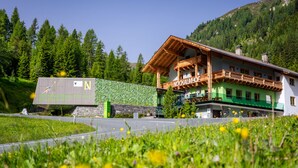 A mountain lodge with a wooden facade, a stone wall, and a signboard. - Idyllic holiday apartments for travel groups (Kremsbrücke)