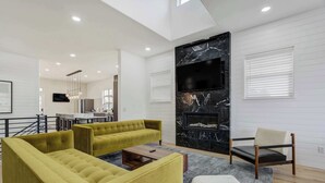 Una sala de estar moderna con un juego de sofá, una mesa de centro, una chimenea y un televisor montado en la pared.