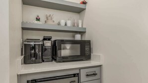 Une petite cuisine équipée avec un réfrigérateur en acier inoxydable, un four à micro-ondes et une machine à café posés sur le plan de travail.