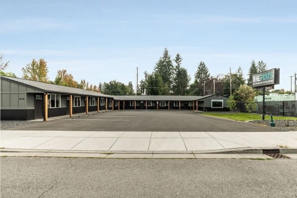 A motel with a row of rooms, a covered parking area, and a sign for 'The Flats'.