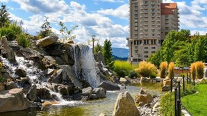 A hotel with a large building, a waterfall, and a pond.