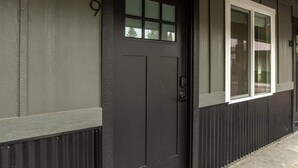 A dark-colored front door with a small window above it, a white-framed window to the right, and a number '9' on the wall to the left.
