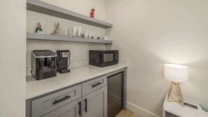 Eine kompakte Küchenzeile mit Kaffeemaschine, Mikrowelle und einer kleinen Ablage für Toilettenartikel.