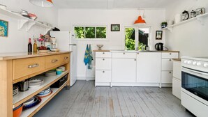 A modern kitchen with white cabinets, a wooden countertop, and a built-in oven. There are two pendant lights, one orange and one white. - "Krister" - 900m from the sea by Interhome (Hasle)