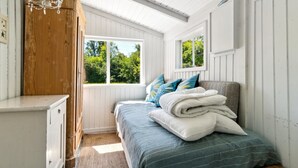 A bedroom with a bed, a wooden wardrobe, a chandelier, and windows with a view of greenery. - "Krister" - 900m from the sea by Interhome (Hasle)
