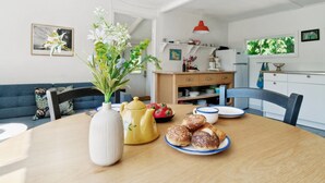 A dining area with a wooden table, a vase with flowers, and a plate of pastries. - "Krister" - 900m from the sea by Interhome (Hasle)