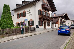 Un bâtiment traditionnel doté d’un balcon, une rue et une voiture garée.