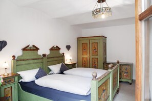 Une chambre avec deux lits, une armoire en bois et un luminaire suspendu.