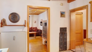 A room with a wooden ceiling, a radiator, a wooden door, and a tiled floor.