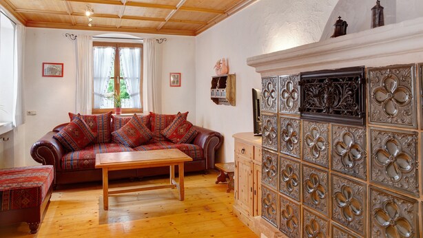 A living room with a wooden ceiling, a sofa, a wooden table, and a decorative cabinet.