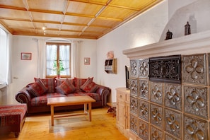 A living room with a wooden ceiling, a sofa, a wooden table, and a decorative cabinet. - Apartment 'Zum Schnitzer Franzl' with Mountain View and Wi-Fi (Garmisch-Partenkirchen)