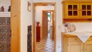 A hallway with a wooden door, a cabinet with glass doors, and a tiled floor.