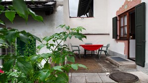 A courtyard with a table and chairs, a door, and a window with shutters.