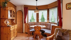 A cozy room with a wooden dining table, chairs, a bench, a cabinet, and a window with curtains. - Apartment 'Nr 2' with Private Terrace, Private Garden and Wi-Fi (Titisee-Neustadt)
