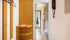 Un corridoio con scaffali in legno, un telefono e una porta che dà su una stanza con vista.