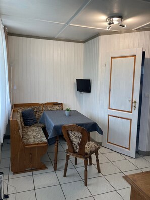 Una habitación con sofá, mesa, silla, televisor y puerta.