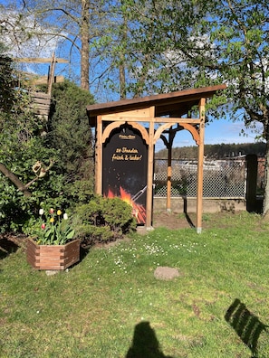 A wooden structure labeled 'Fool-Box' with a sign stating '24 Stunden frisch & lecker!' surrounded by greenery and a fenced area. - Bungalow 'B 5' with Private Terrace and Wi-Fi (Rheinsberg)