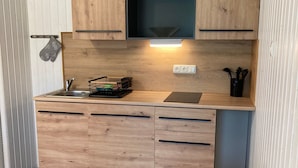 Kompakti keittokomero, jossa on puukaapit, sisäänrakennettu mikroaaltouuni ja pieni työtaso.