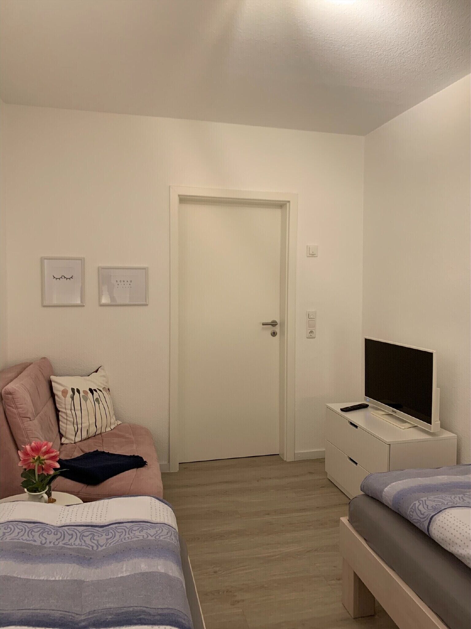 Une chambre à coucher avec un lit, une télévision, une commode et une porte.