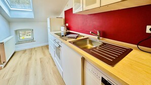 Una cocina moderna con una pared roja de acento, un tragaluz y un lavavajillas.