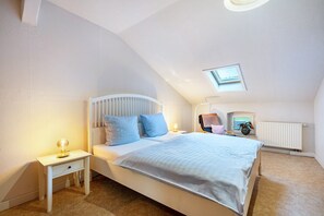 Ein Schlafzimmer mit Bett, Nachttisch, Lampe und einem kleinen Fenster.