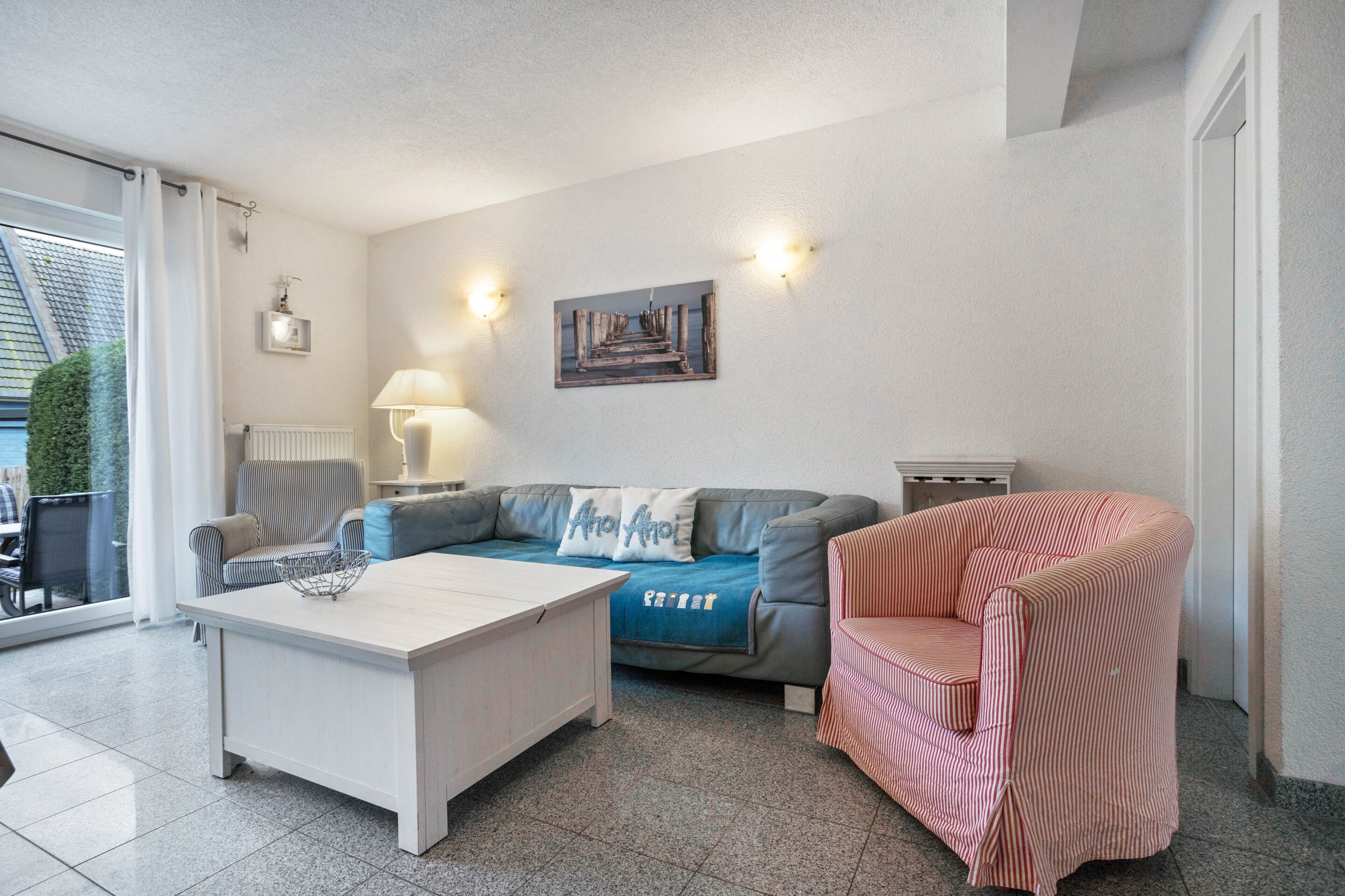 Ein Wohnzimmer mit einer Couch, einem gestreiften Sessel, einem Couchtisch und einem Bild an der Wand.