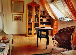 Une pièce chaleureuse avec une bibliothèque en bois, un fauteuil en osier et une table ronde.
