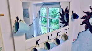 A room with a window, a wall-mounted shelf with mugs, and a decorative wall piece. - Holiday Apartment Mulleby with Shared Garden and Wi-Fi (Süderhackstedt)