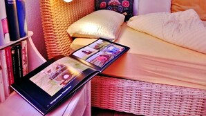 A cozy bedroom with a bed, a bedside lamp, a tablet displaying a photo, and a bookshelf with books. - Holiday Apartment Mulleby with Shared Garden and Wi-Fi (Süderhackstedt)