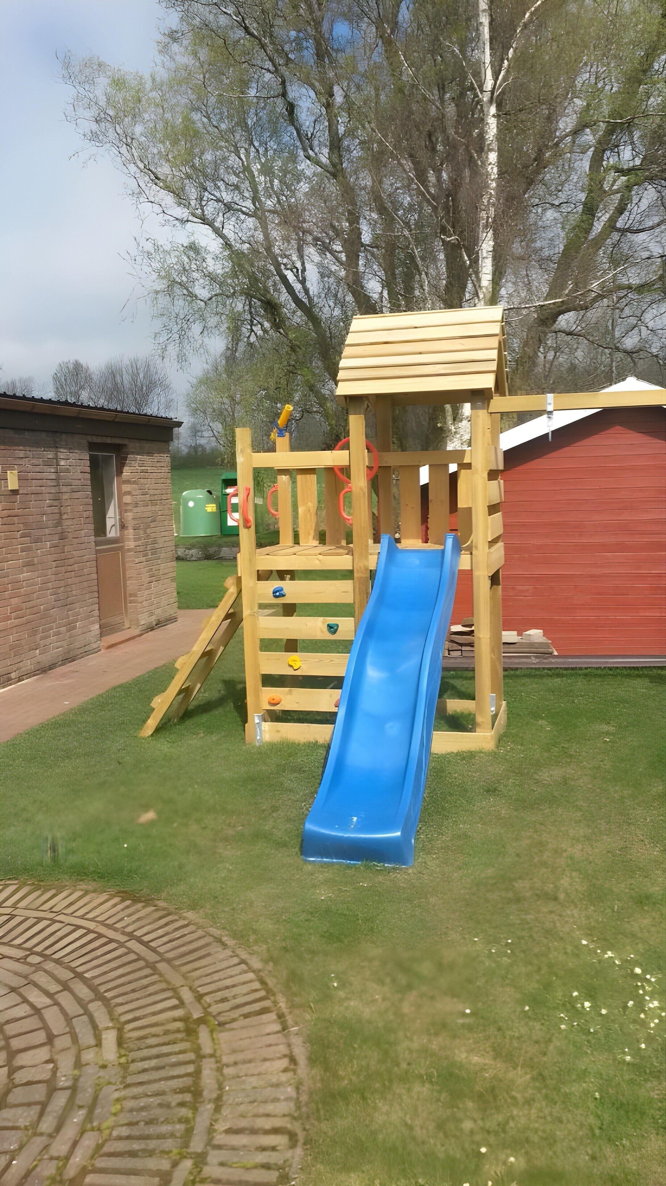 Ein Spielplatz mit Rutsche, Kletterbereich und einer kleinen Holzkonstruktion.