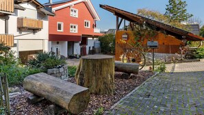 A red building with a white garage door, a wooden bench, and a large tree stump.