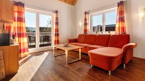 Un salon avec un canapé, une table basse, un téléviseur et un plafond en bois.