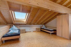 A loft bedroom with a skylight, two beds, a wardrobe, and a floor lamp.