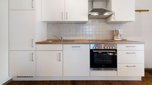 A modern kitchen with white cabinets, a stainless steel oven, and a wooden countertop. - Apartment 'Ferienwohnung Traube' with Shared Garden, Balcony and Wi-Fi (Appenweier)