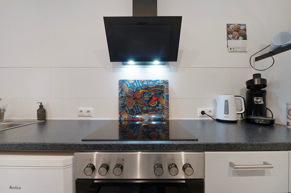 Eine Küche mit einem modernen Herd, einer Kaffeemaschine und einer farbenfrohen Spritzschutzwand.