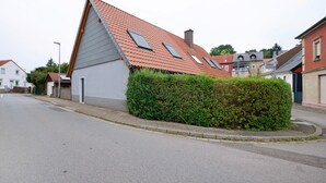 Asuinrakennus, jossa on kalteva katto, useita ikkunoita ja hyvin hoidettu pensasaita.