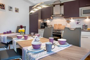 Una cocina moderna con una mesa de comedor preparada para cuatro personas, con vajilla morada y blanca.