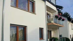 Een meerlaags gebouw met balkons, ramen en een kleine tuin.
